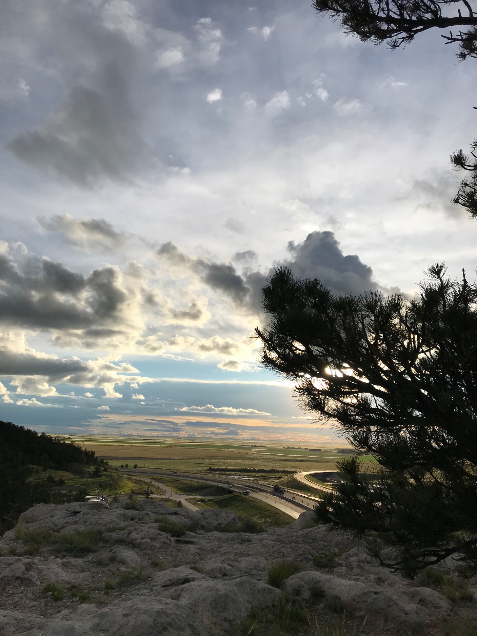 Farmland beneath clouds viewed from a rocky overlook